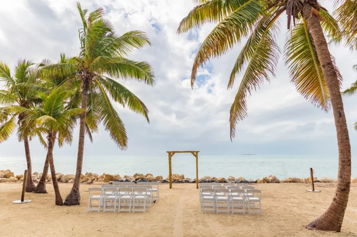 Beach wedding ceremony setup under palm trees in the Florida Keys. Change your name with HitchSwitch